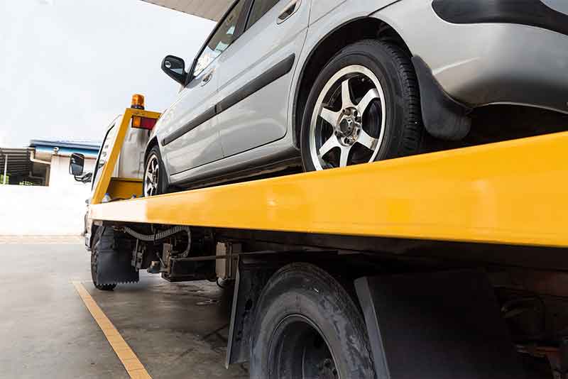 Kaputtes Auto auf einem Pritschenabschleppwagen wird zur Reparatur transportiert