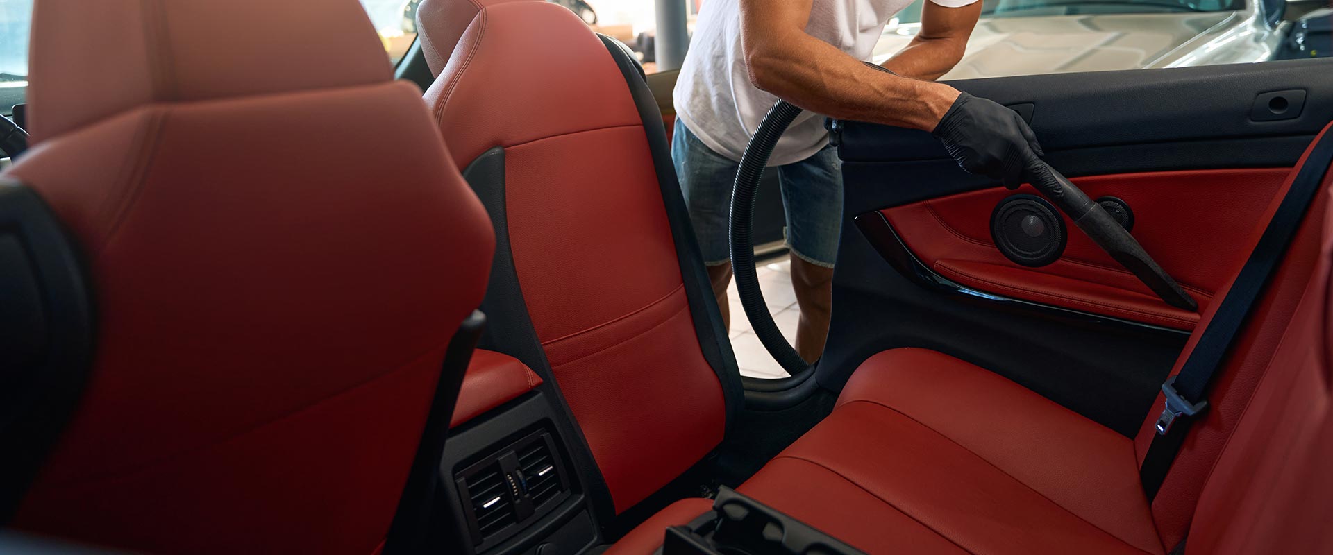Mann in Schutzhandschuhen saugt das Innere eines Autos ab