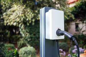 Inmitten einer üppigen Gartenanlage wurde eine Ladestation für Elektrofahrzeuge mit schwarzem Ladekabel installiert